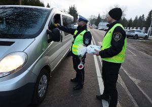 Policjant sprawdza trzeźwość kierującego. Obok stoi funkcjonariusz Straży Miejskiej