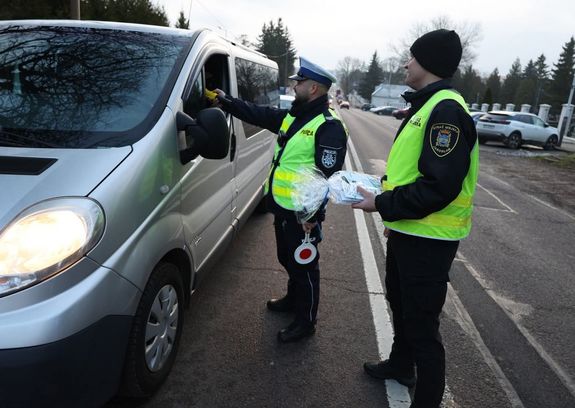 Policjant sprawdza trzeźwość kierującego. Obok stoi funkcjonariusz Straży Miejskiej