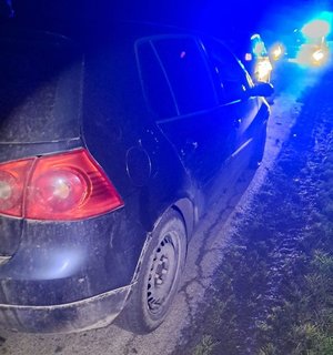 Zdjęcie wykonane nocą. Po lewej stronie widoczna jest cześć pojazdu. Po prawej stronie w oddali błysk niebieskich świateł