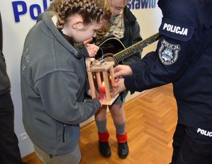 Policjant i harcerka. Dziewczynka przekazują policjantowi światło pokoju.