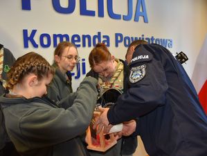 Policjant przyjmuje od harcerki światło pokoju