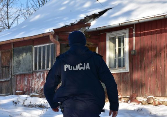 Policjant. W tle opuszczony budynek