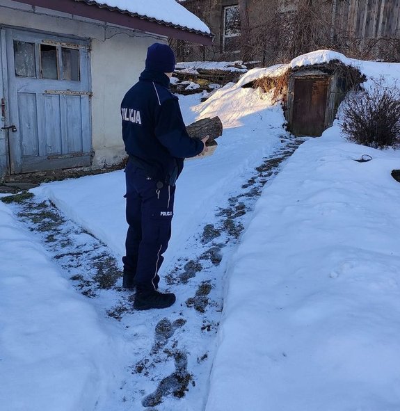 Policjant niesie drzewno opałowe