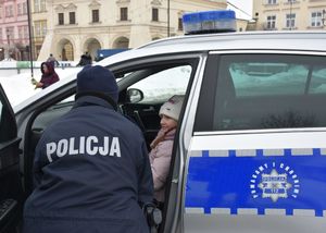 Dziecko w  radiowozie. Przy pojeździe stoi policjantka