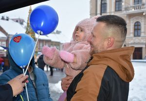 Mężczyzna z dzieckiem na rękach przy policyjnym stoisku