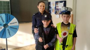 Policjantka z dziećmi ubranymi w elementy policyjnego umundurowania