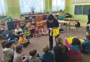 Policjantka rozdaje dzieciom kamizelki odblaskowe