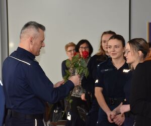 Policjant wręcza różę kobiecie