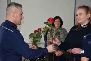 Policjant wręcza różę policjantce