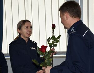 Policjant wręcza różę policjantce