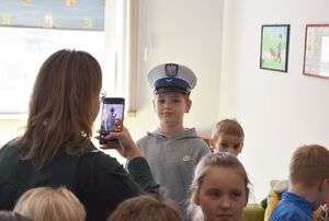 Kobieta robi zdjęcie chłopcu który ma na głowie policyjną czapkę