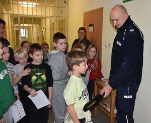 Policjant i dzieci w pomieszczeniu dla osób zatrzymanych