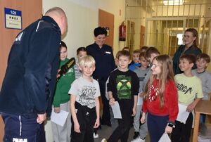 Policjant z dziećmi w pomieszczeniu dla osób zatrzymanych