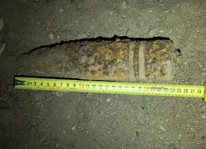 Skorodowany pocisk przy którym znajduje się metr