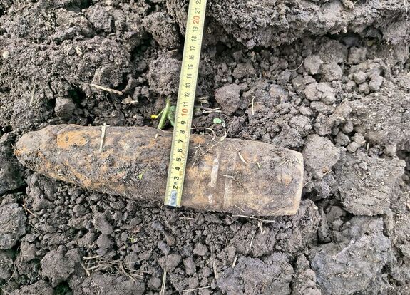 Mocno skorodowany pocisk, przy którym znajduje się metr