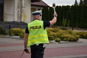 Policjant daje sygnał tarczą do zatrzymania kierującemu pojazdem