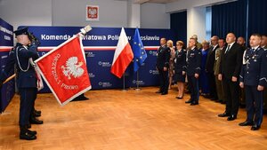 Aula na której znajdują się policjanci, policjantki, zaproszeni goście oraz poczet sztandarowy Policji