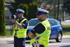 Policjanci  jarosławskiej drogówki w trakcie pełnienia służby na drodze, jeden z policjantów mierzy prędkość przejeżdżającym pojazdom.