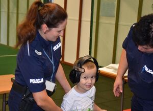 Policjantki z chłopczykiem. Chłopiec ma założone słuchawki