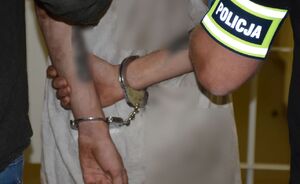 Policjanci prowadzą zatrzymanego mężczyznę.