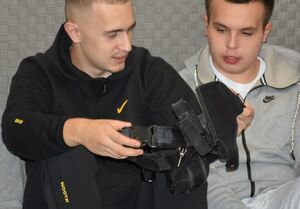 Dwóch uczniów zapoznaje się z elementami policyjnego umundurowania